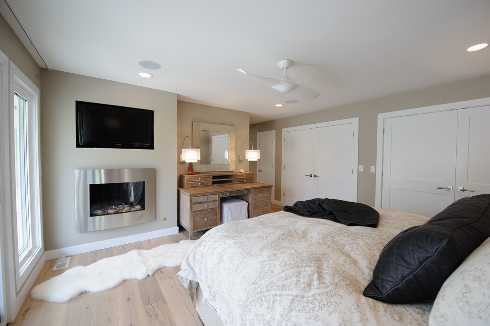 Cette image montre une chambre parentale design de taille moyenne avec un mur beige, parquet clair, une cheminée standard, un manteau de cheminée en métal et un sol marron.