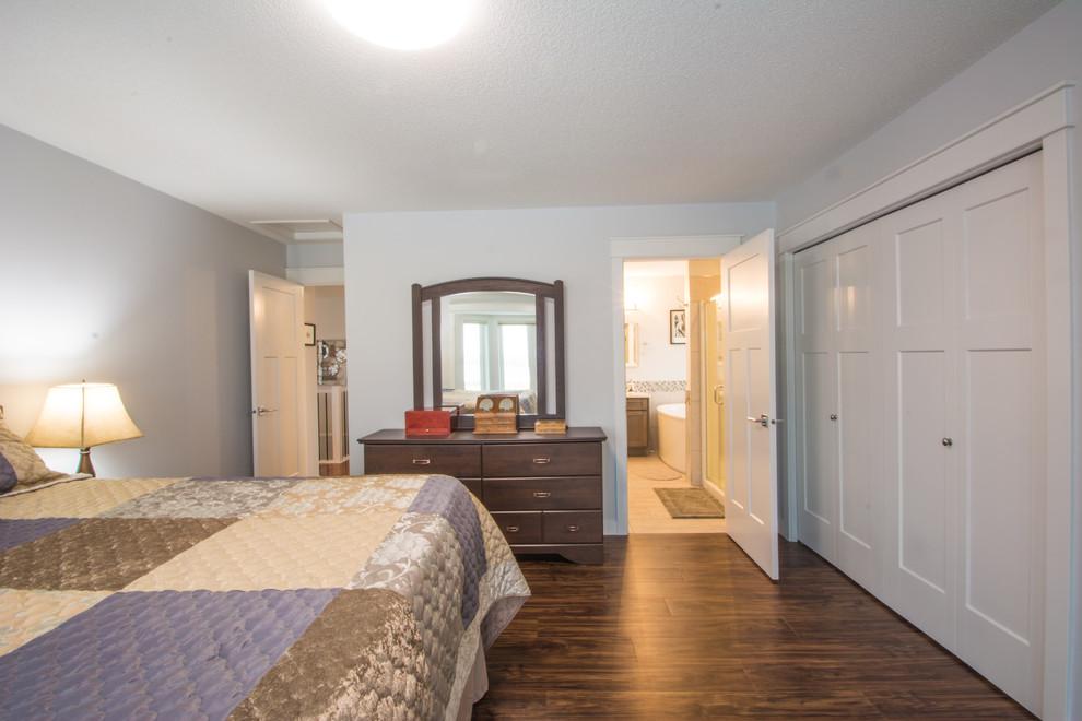 Medium sized traditional master bedroom with grey walls, medium hardwood flooring, no fireplace and brown floors.