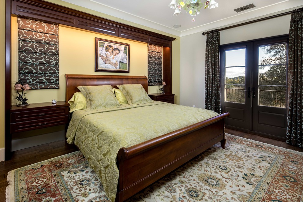 На фото: хозяйская спальня среднего размера в классическом стиле с желтыми стенами и темным паркетным полом без камина