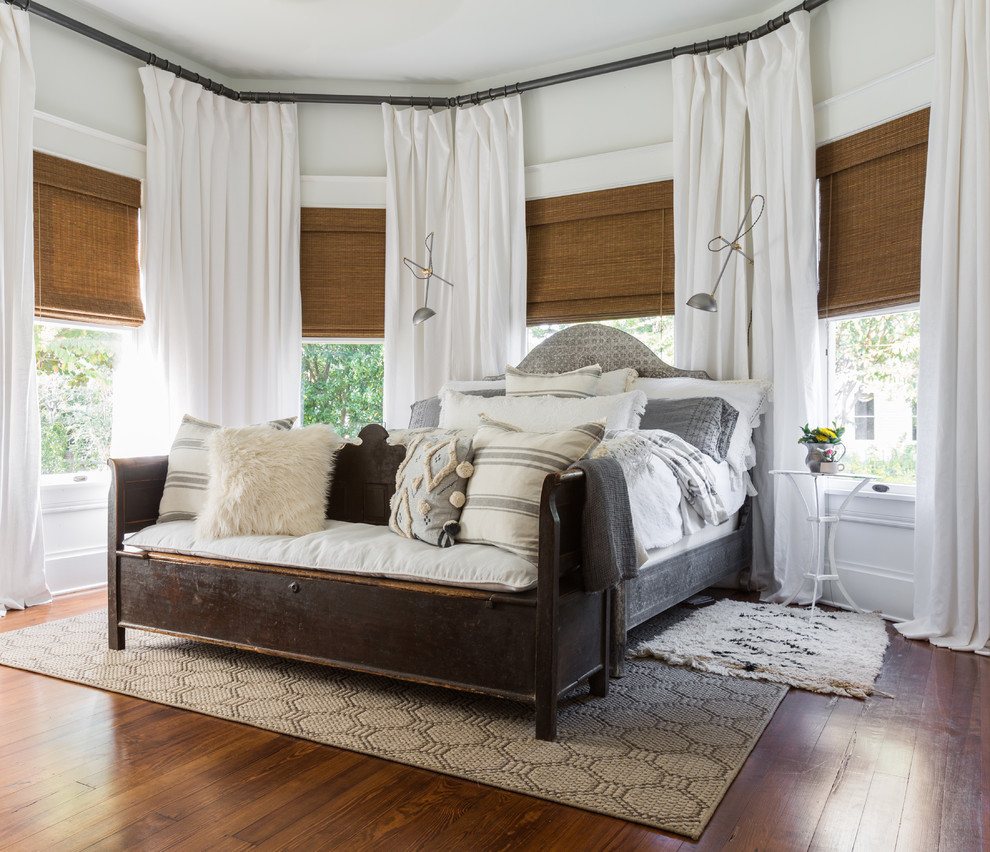 Modelo de dormitorio principal de estilo americano de tamaño medio con paredes blancas, suelo de madera oscura y suelo marrón