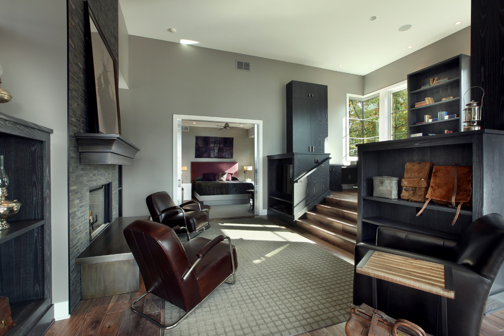 Großes Modernes Gästezimmer mit grauer Wandfarbe, braunem Holzboden, Kamin und Kaminumrandung aus Stein in Grand Rapids