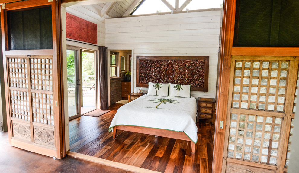 Imagen de dormitorio principal tropical grande con paredes blancas y suelo de madera en tonos medios