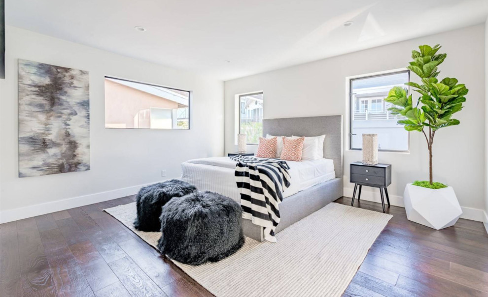 Großes Modernes Gästezimmer mit weißer Wandfarbe, braunem Holzboden und braunem Boden in Orange County