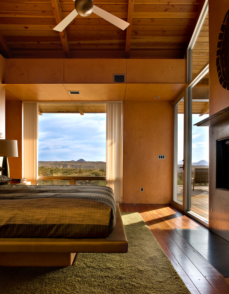 Modelo de dormitorio contemporáneo con paredes beige y suelo de madera en tonos medios