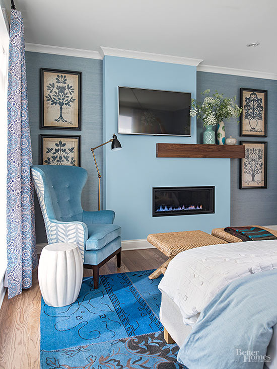 Exemple d'une chambre parentale tendance de taille moyenne avec un mur bleu, une cheminée ribbon, parquet clair, un manteau de cheminée en métal et un sol bleu.