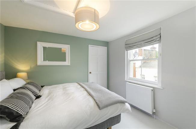 Photo of a medium sized traditional guest bedroom in London with green walls and painted wood flooring.