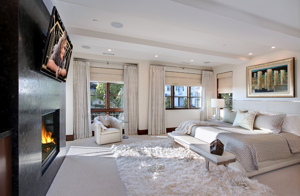 Immagine di una camera da letto minimal con pareti bianche, moquette, camino classico e TV