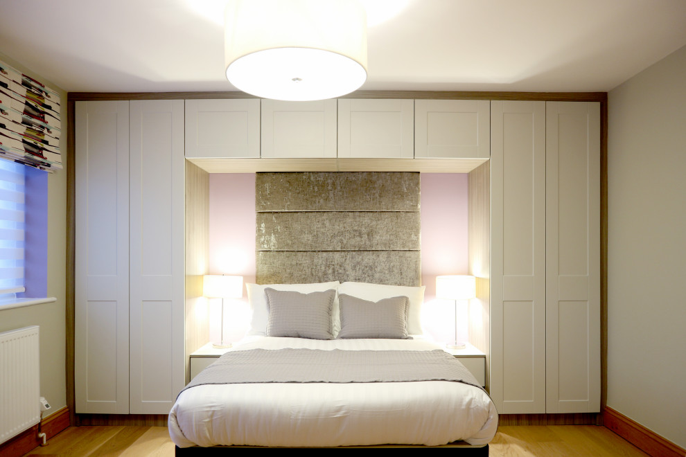 Design ideas for a large modern guest and grey and purple bedroom in Hertfordshire with grey walls, medium hardwood flooring, no fireplace, brown floors and a feature wall.