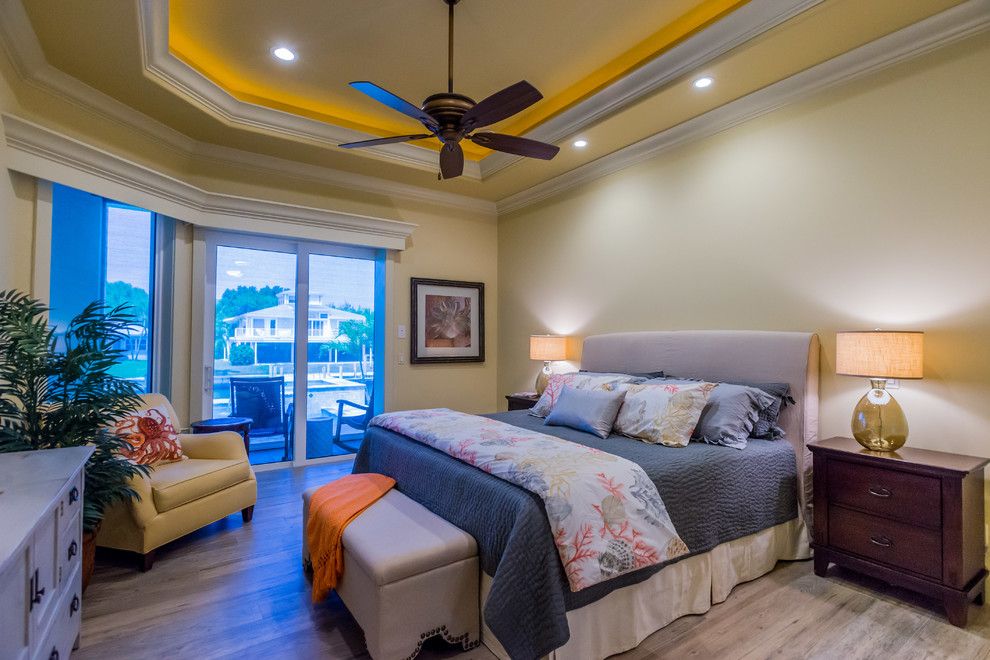 Diseño de dormitorio principal costero grande sin chimenea con paredes amarillas y suelo de baldosas de cerámica
