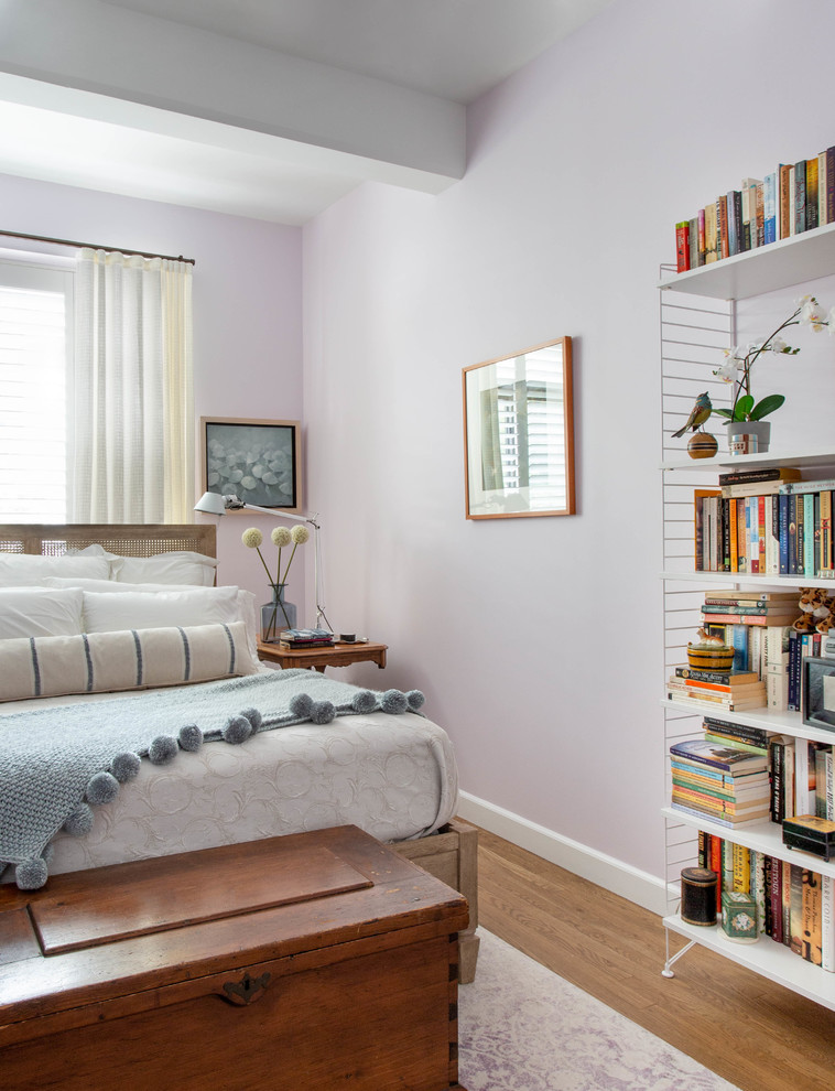 Immagine di una piccola camera matrimoniale con pareti viola, pavimento in legno massello medio, nessun camino e pavimento marrone