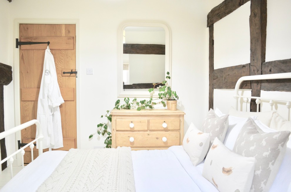 Esempio di una piccola camera degli ospiti country con pareti bianche, pavimento in legno verniciato, nessun camino e pavimento beige