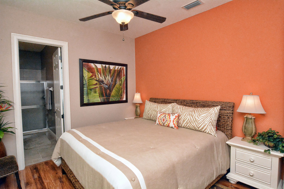 タンパにある中くらいなトロピカルスタイルのおしゃれな客用寝室 (オレンジの壁、無垢フローリング、暖炉なし)