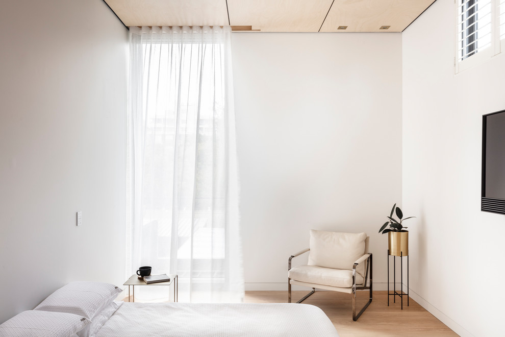 Exempel på ett modernt sovrum, med vita väggar, ljust trägolv och beiget golv