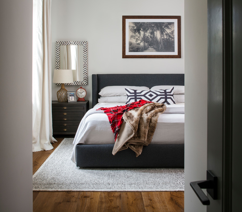 Example of a trendy medium tone wood floor and brown floor bedroom design in San Diego with white walls