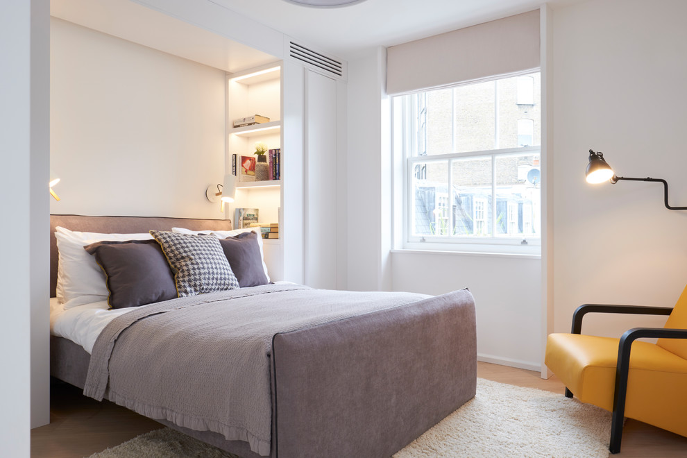 Modelo de dormitorio actual de tamaño medio sin chimenea con paredes blancas y suelo de madera clara
