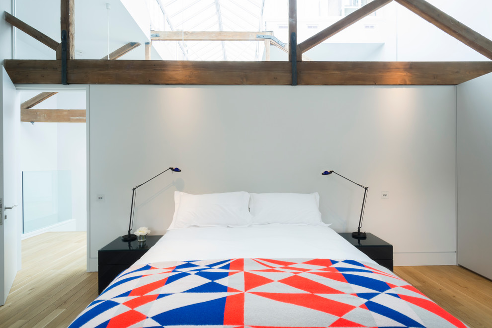 Geräumiges Industrial Schlafzimmer im Loft-Style mit weißer Wandfarbe und hellem Holzboden in London