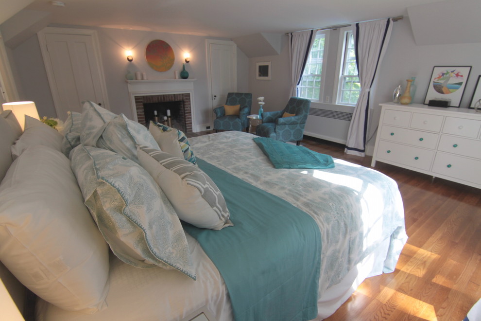 Imagen de dormitorio principal clásico renovado de tamaño medio con paredes grises, suelo de madera clara, todas las chimeneas y marco de chimenea de ladrillo