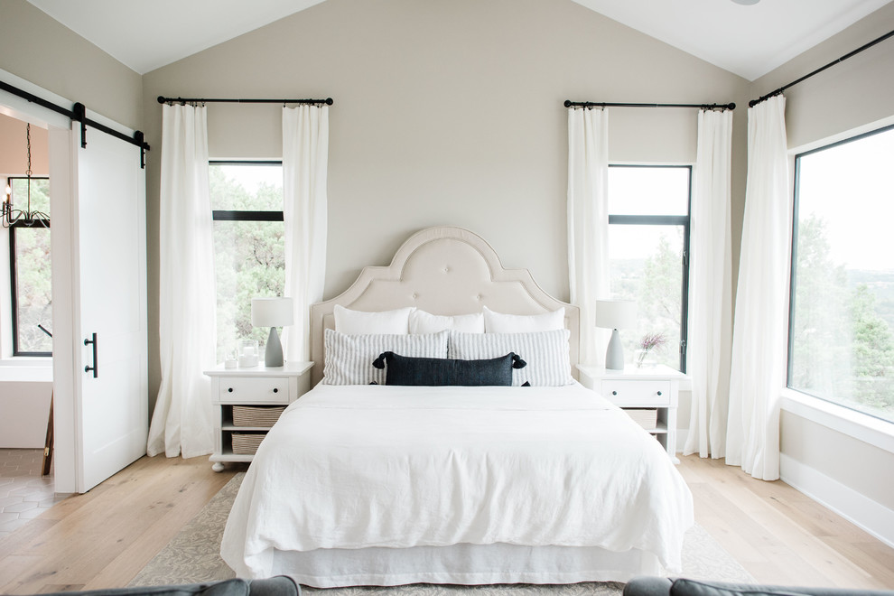 Источник вдохновения для домашнего уюта: большая хозяйская спальня в стиле кантри с серыми стенами, светлым паркетным полом, стандартным камином, фасадом камина из камня и коричневым полом