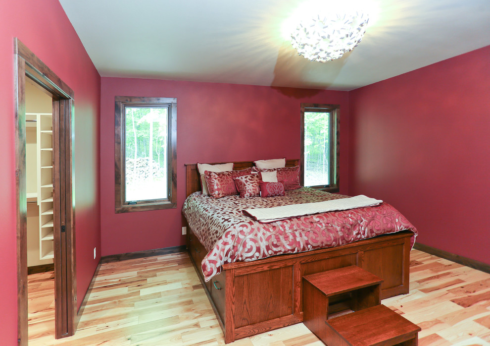 Modelo de dormitorio principal actual de tamaño medio con paredes rojas y suelo de madera en tonos medios