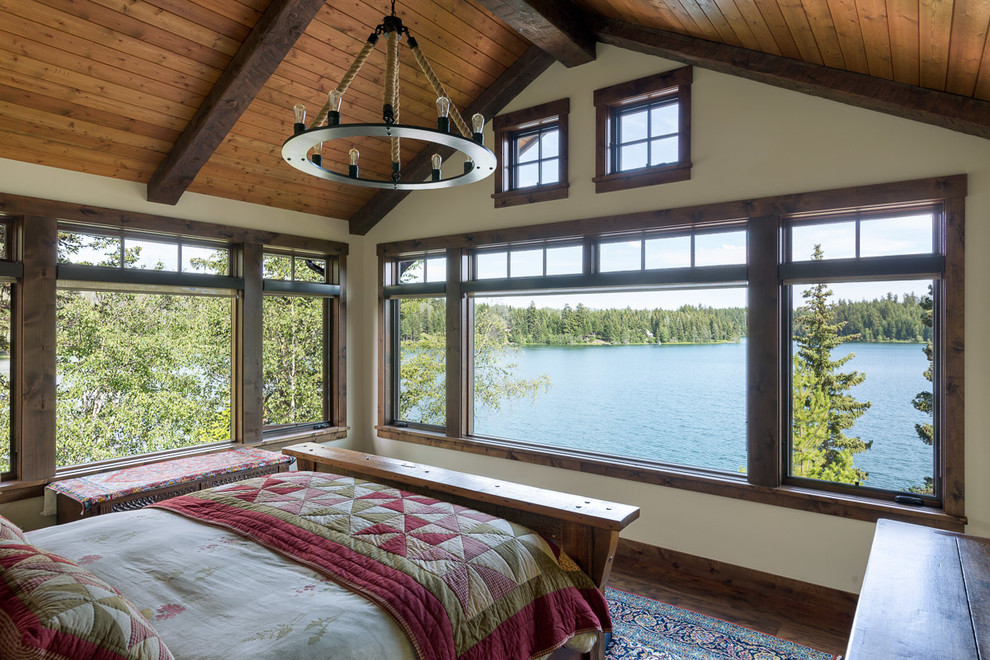 Imagen de dormitorio principal rural de tamaño medio con paredes beige, suelo de madera en tonos medios y suelo marrón