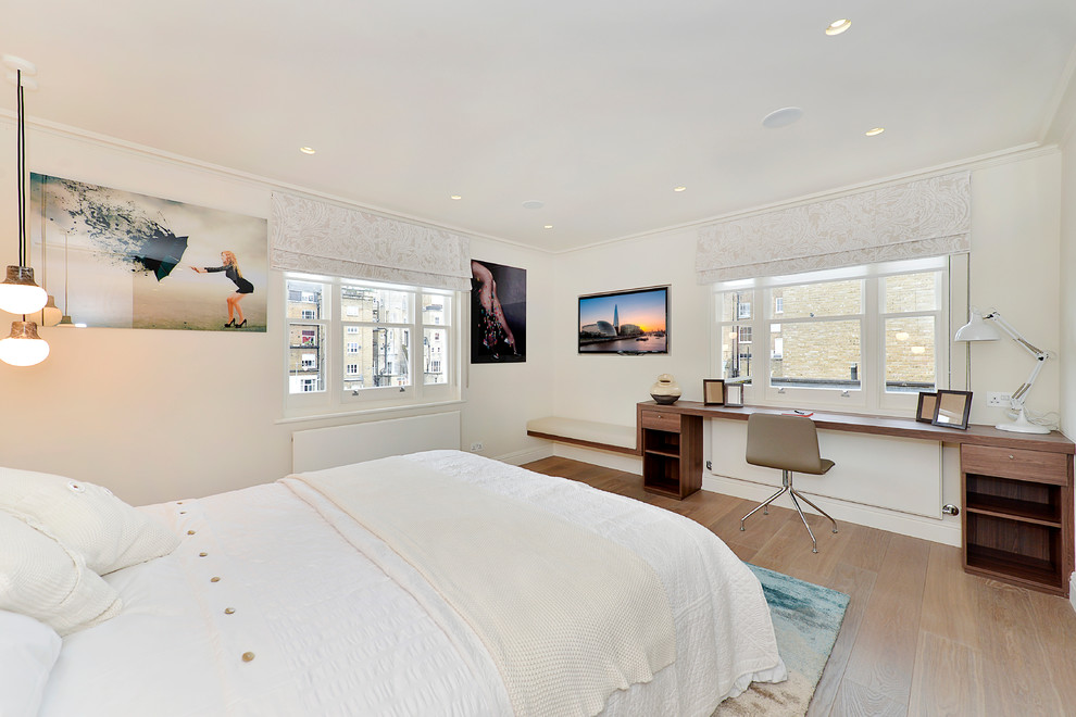 Example of a mid-sized trendy guest light wood floor bedroom design in London with white walls