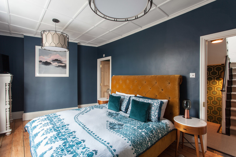 This is an example of an eclectic bedroom in London with blue walls, medium hardwood flooring and brown floors.