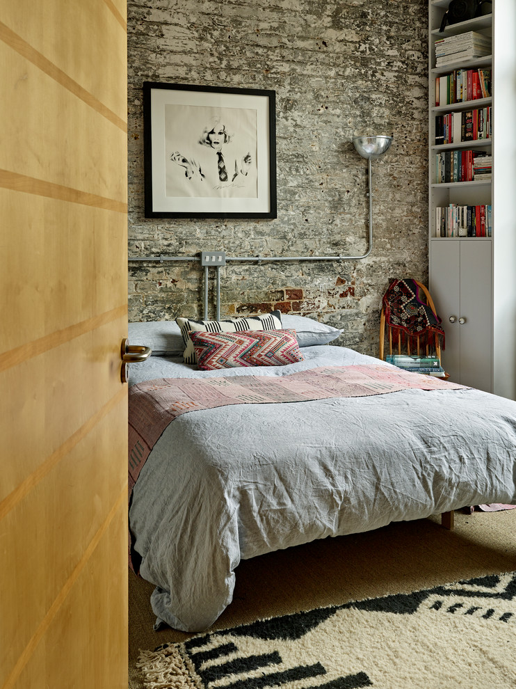 Design ideas for an industrial guest and grey and brown bedroom in London with grey walls and brown floors.
