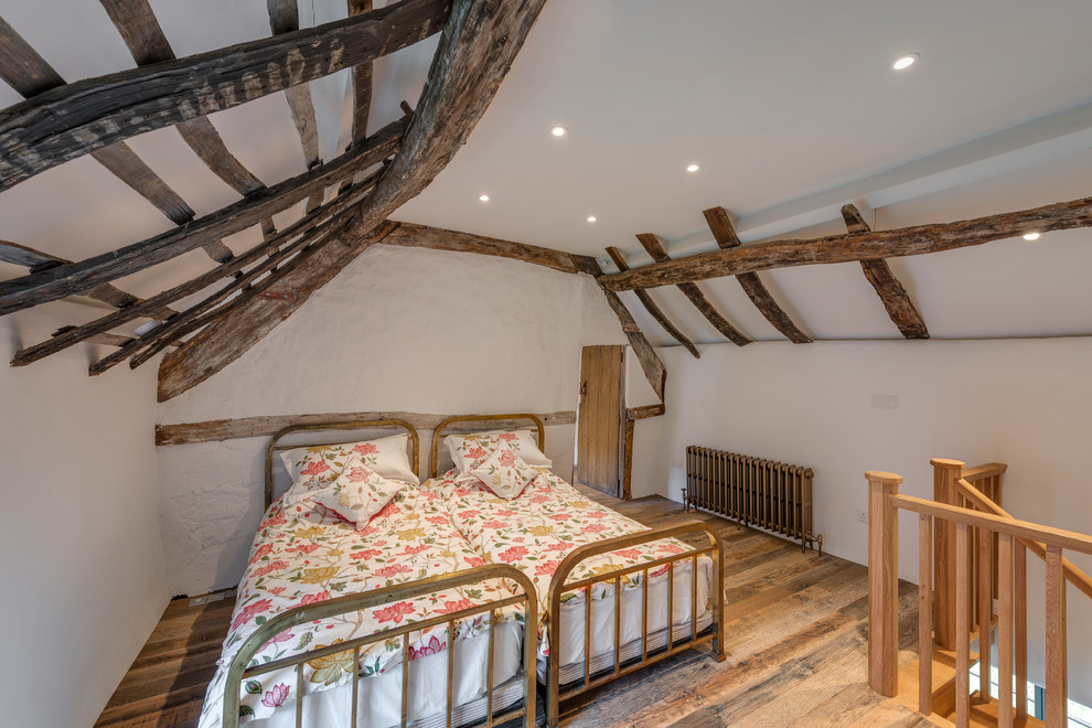 Design ideas for a rural mezzanine loft bedroom in Cornwall with white walls, medium hardwood flooring and brown floors.
