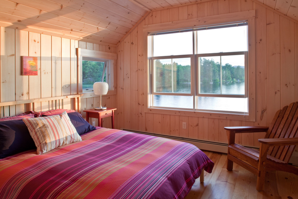 This is an example of a rustic guest bedroom in Portland Maine with beige walls and medium hardwood flooring.