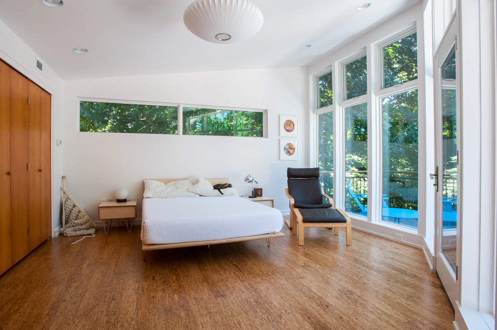Modernes Schlafzimmer mit weißer Wandfarbe und braunem Holzboden in Sonstige