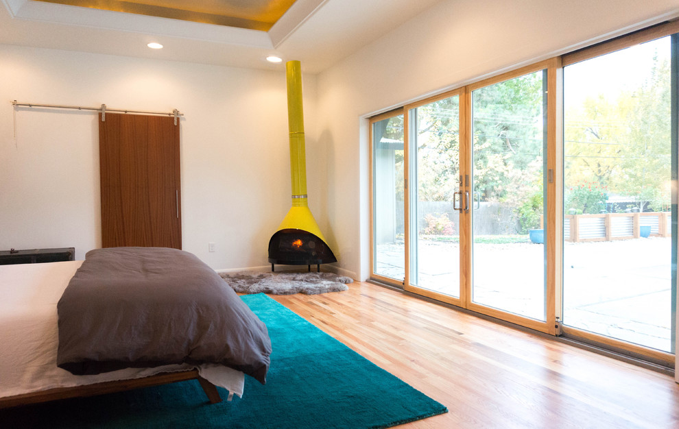 ボイシにある広いミッドセンチュリースタイルのおしゃれな主寝室 (白い壁、無垢フローリング、コーナー設置型暖炉) のインテリア