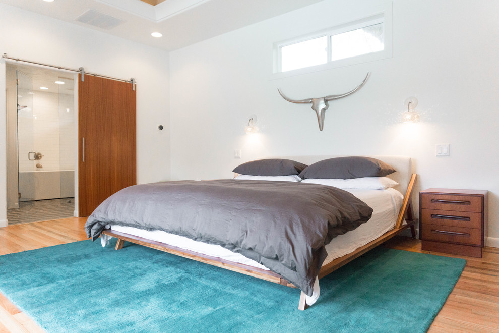 Großes Mid-Century Hauptschlafzimmer mit weißer Wandfarbe, braunem Holzboden und beigem Boden in Boise
