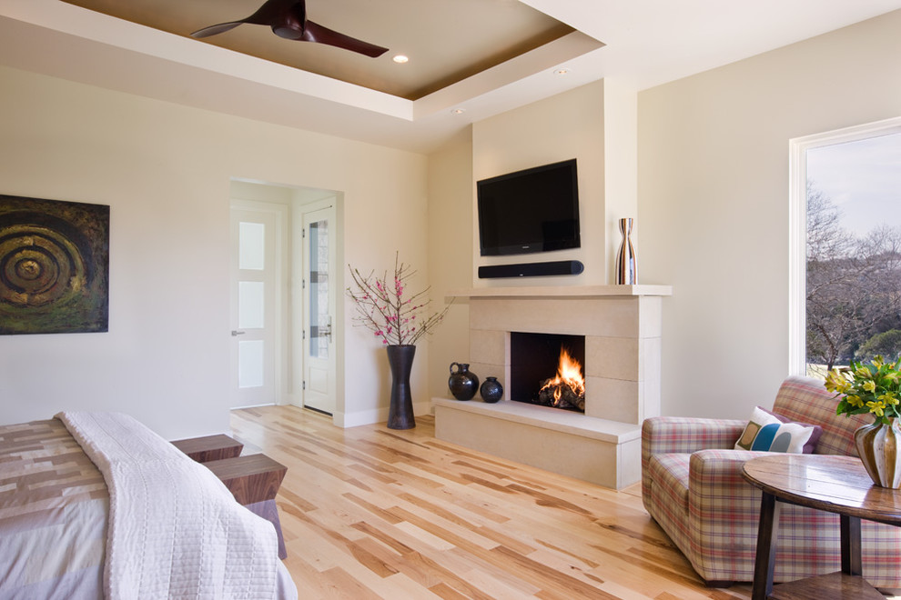Diseño de dormitorio televisión contemporáneo con paredes blancas, suelo de madera clara y suelo beige