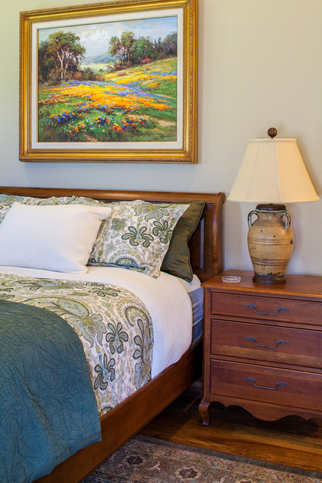 Immagine di una camera degli ospiti chic di medie dimensioni con pareti beige e pavimento in legno massello medio