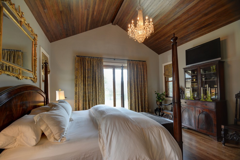 Modelo de dormitorio principal campestre de tamaño medio sin chimenea con paredes beige, suelo de madera en tonos medios y suelo marrón