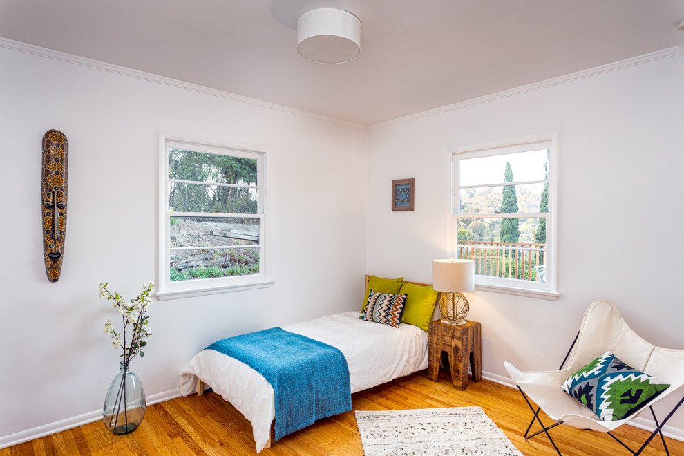 Diseño de habitación de invitados contemporánea pequeña con paredes blancas y suelo de madera clara