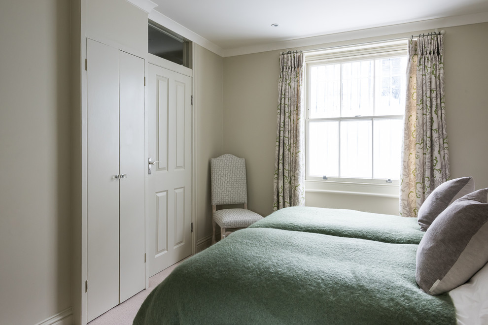 This is an example of a medium sized vintage guest bedroom in London with green walls, carpet and no fireplace.