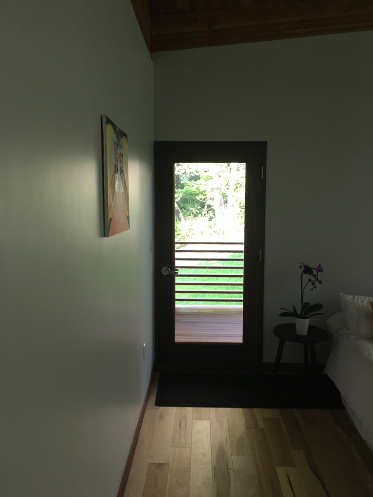 Diseño de habitación de invitados minimalista de tamaño medio sin chimenea con paredes blancas, suelo de madera clara y suelo beige