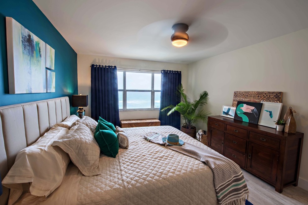 マイアミにある中くらいなビーチスタイルのおしゃれな主寝室 (青い壁、磁器タイルの床、グレーの床)