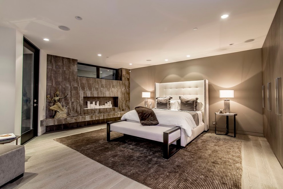 ロサンゼルスにある広いコンテンポラリースタイルのおしゃれな主寝室 (茶色い壁、無垢フローリング、横長型暖炉、タイルの暖炉まわり)