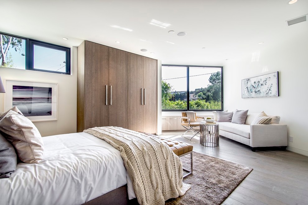 Großes Modernes Hauptschlafzimmer ohne Kamin mit weißer Wandfarbe und braunem Holzboden in Los Angeles