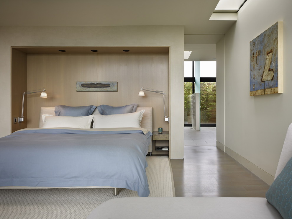 Diseño de habitación de invitados moderna sin chimenea con paredes blancas y suelo de madera clara