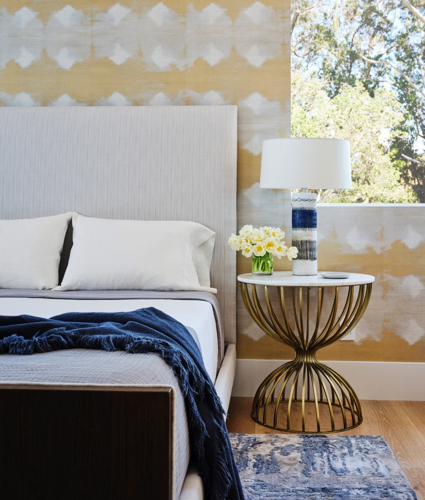 Diseño de habitación de invitados actual con paredes amarillas, suelo de madera clara, suelo marrón y papel pintado