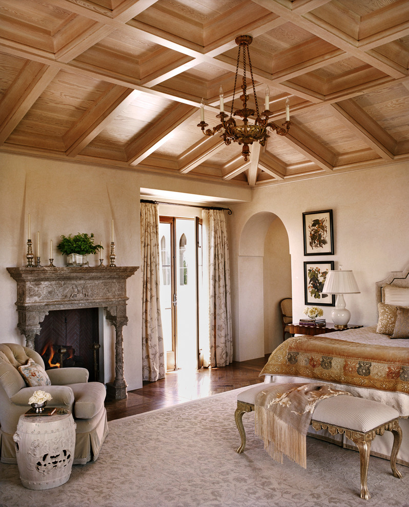 Imagen de dormitorio principal, mediterráneo, con paredes beige, suelo de madera en tonos medios y todas las chimeneas