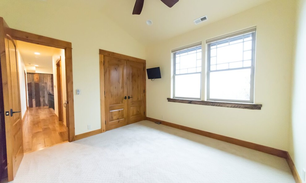 Imagen de habitación de invitados rústica de tamaño medio sin chimenea con paredes beige y suelo de travertino