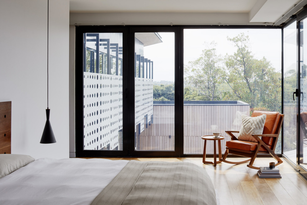 Idée de décoration pour une chambre parentale design de taille moyenne avec un mur blanc, un sol en bois brun et un sol orange.