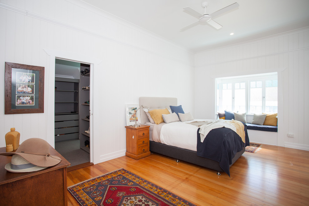 Foto di una camera degli ospiti tropicale di medie dimensioni con pareti bianche e pavimento in legno massello medio