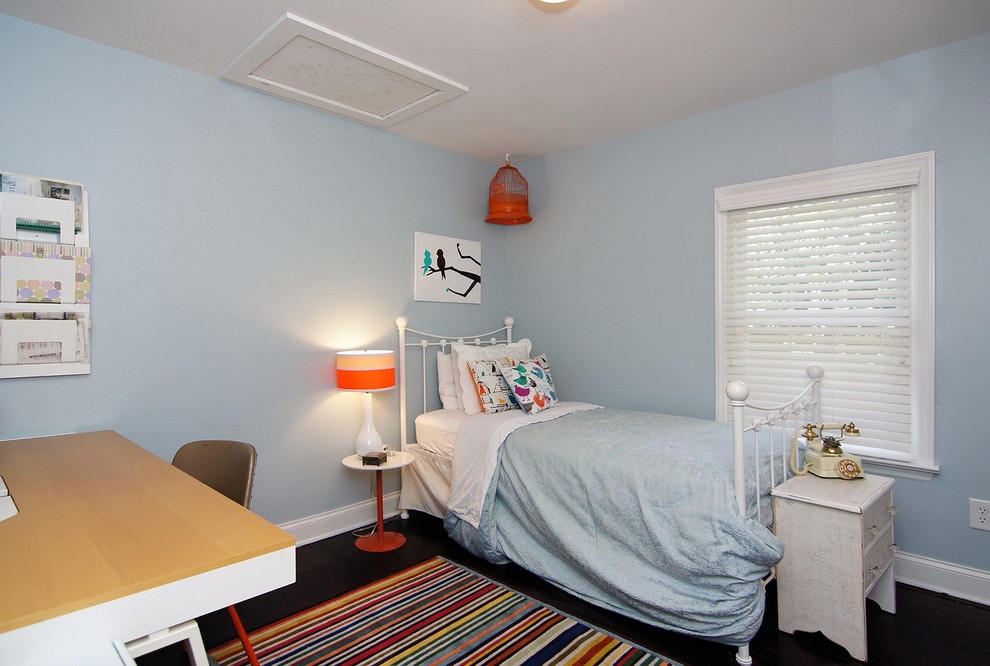 Design ideas for a small contemporary guest bedroom in Raleigh with blue walls, dark hardwood flooring, a standard fireplace, a wooden fireplace surround and brown floors.