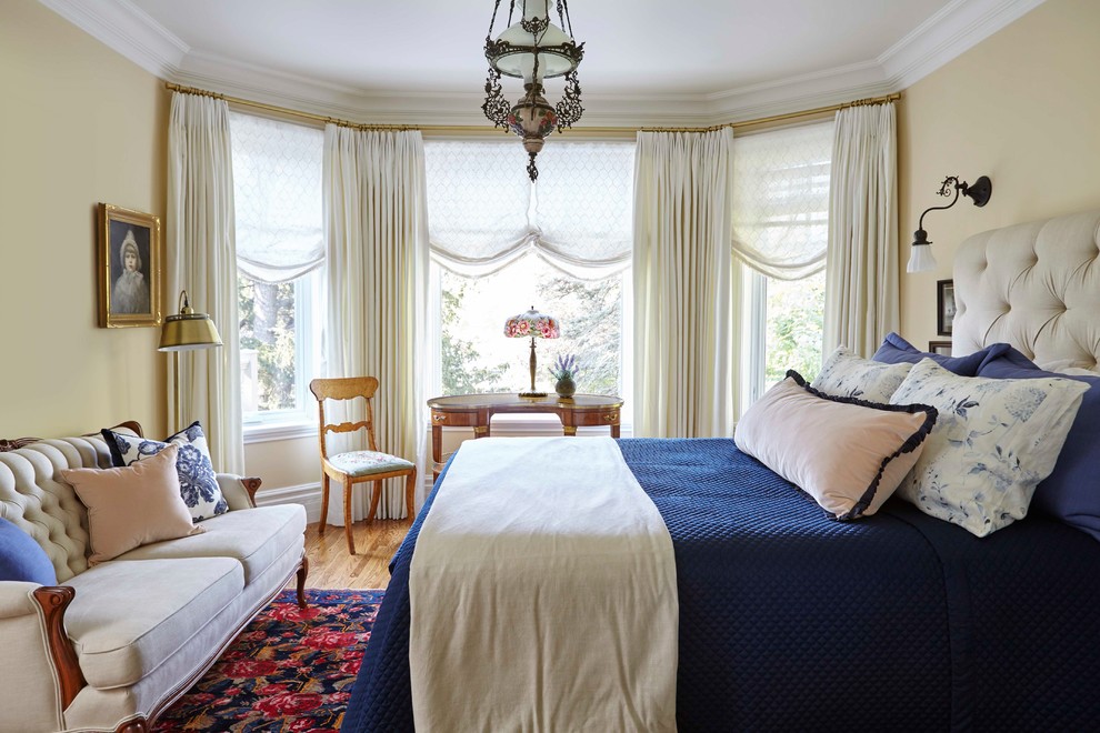 Ejemplo de habitación de invitados tradicional de tamaño medio con paredes amarillas, suelo de madera en tonos medios y suelo marrón