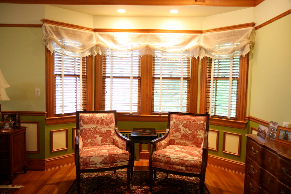 Immagine di un'ampia camera matrimoniale tradizionale con pareti verdi e pavimento in legno massello medio